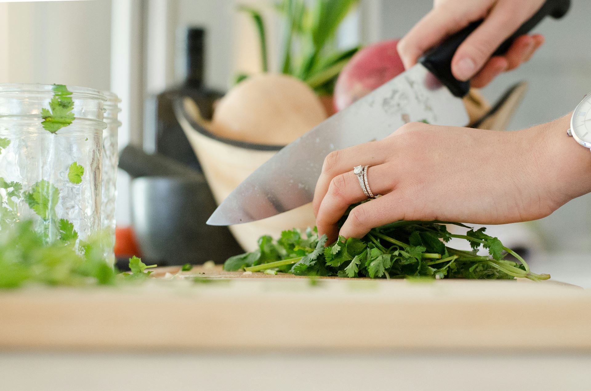 A person in a kitchen cutting up vegetable with a chopping knife