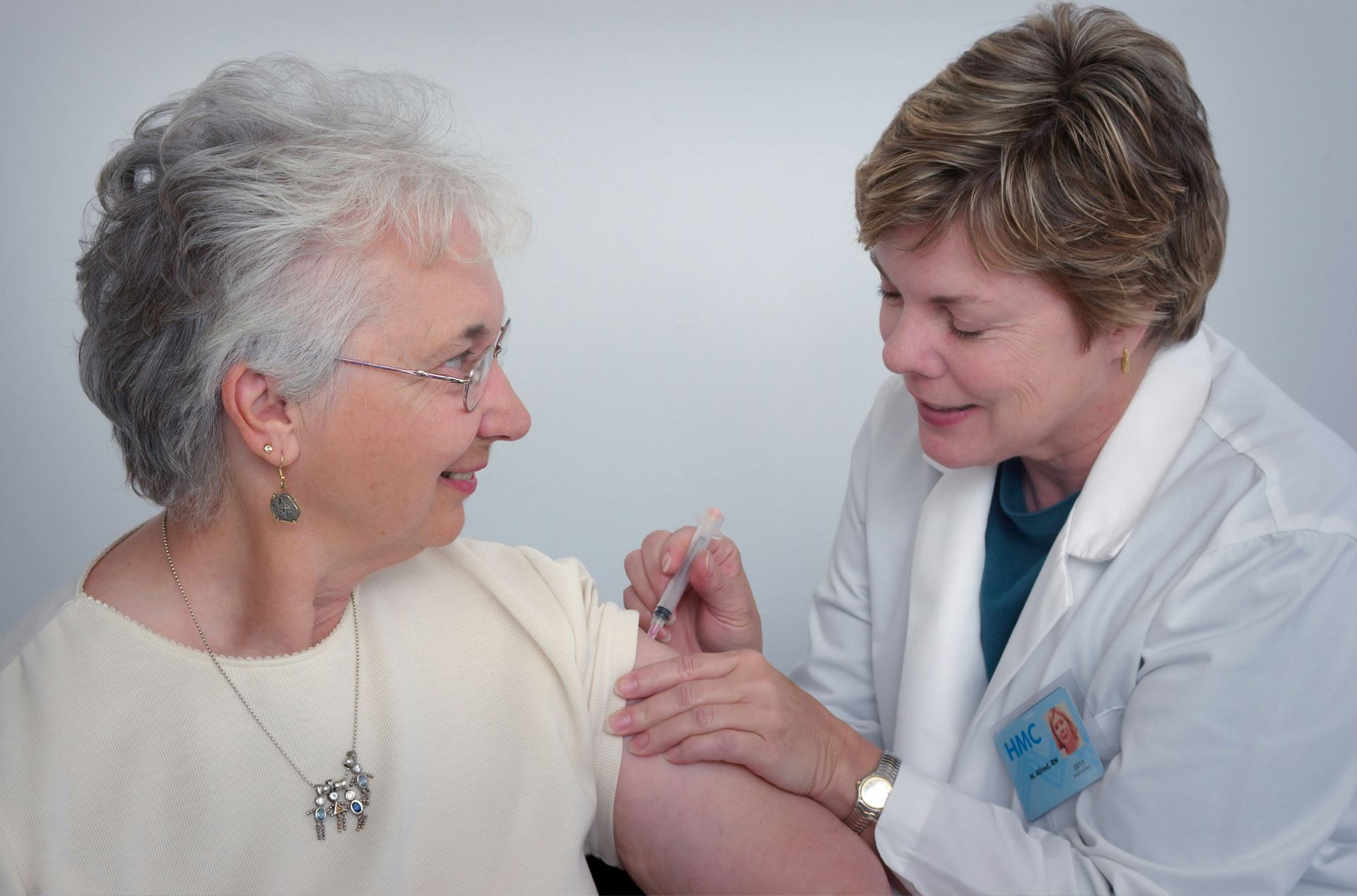 A women receiving a flu vaccine in her left arm from a medical professional